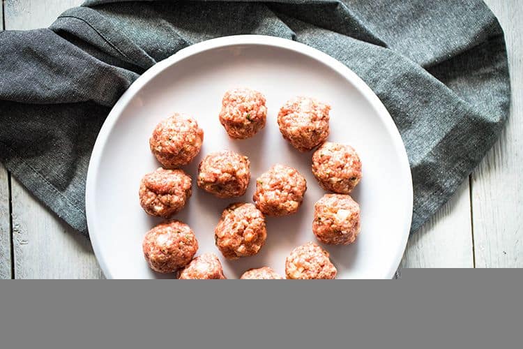 uncooked meatballs on a white plate