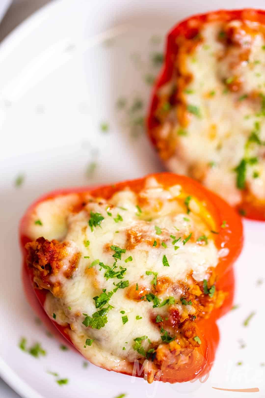 Cheesy turkey stuffed peppers baked to perfection, topped with fresh parsley on a white plate.