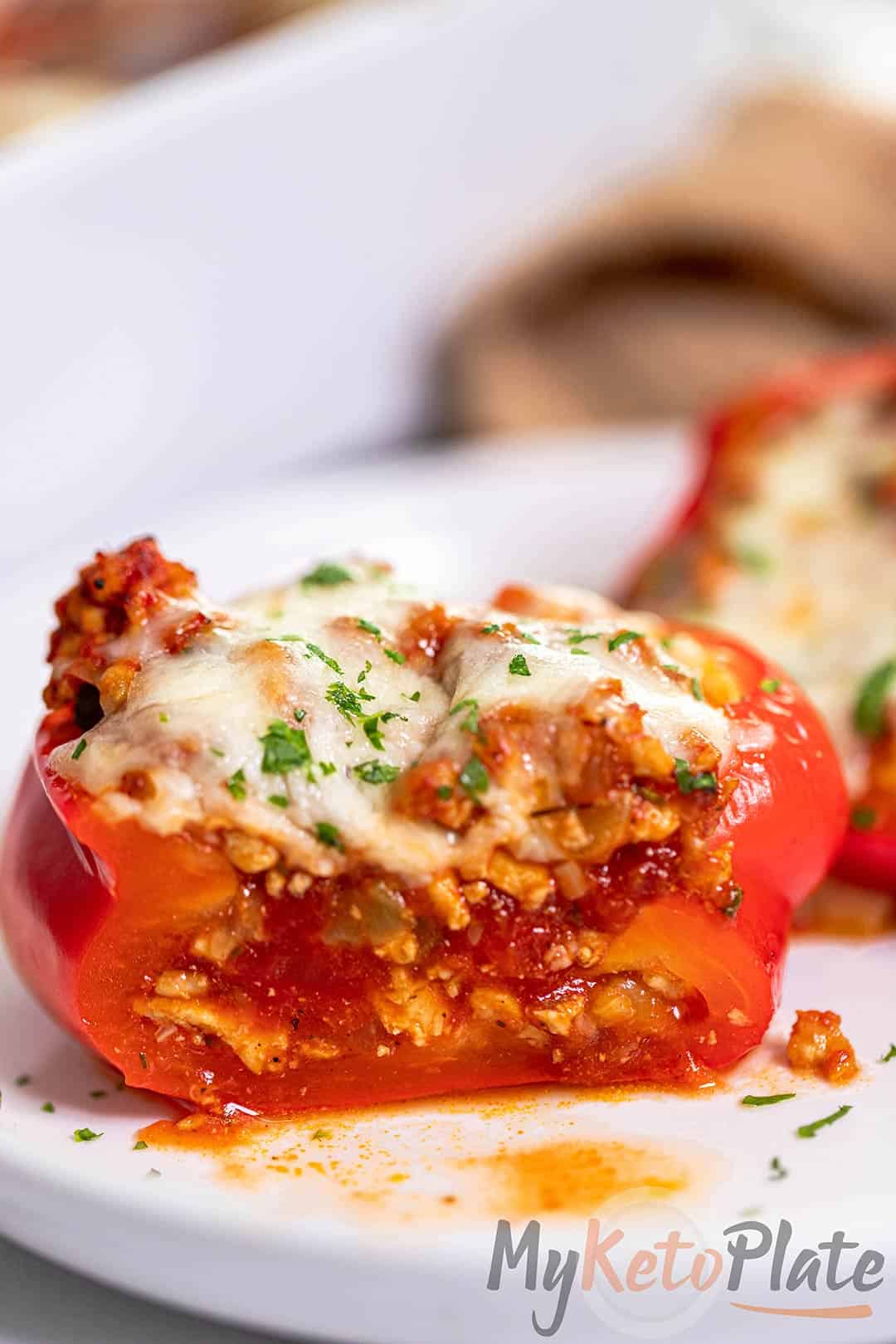 A stuffed red bell pepper cut in half, revealing juicy turkey filling with marinara sauce and cheese.