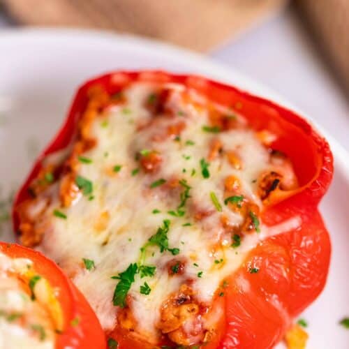 A perfectly baked turkey stuffed pepper served on a white plate, topped with fresh parsley.