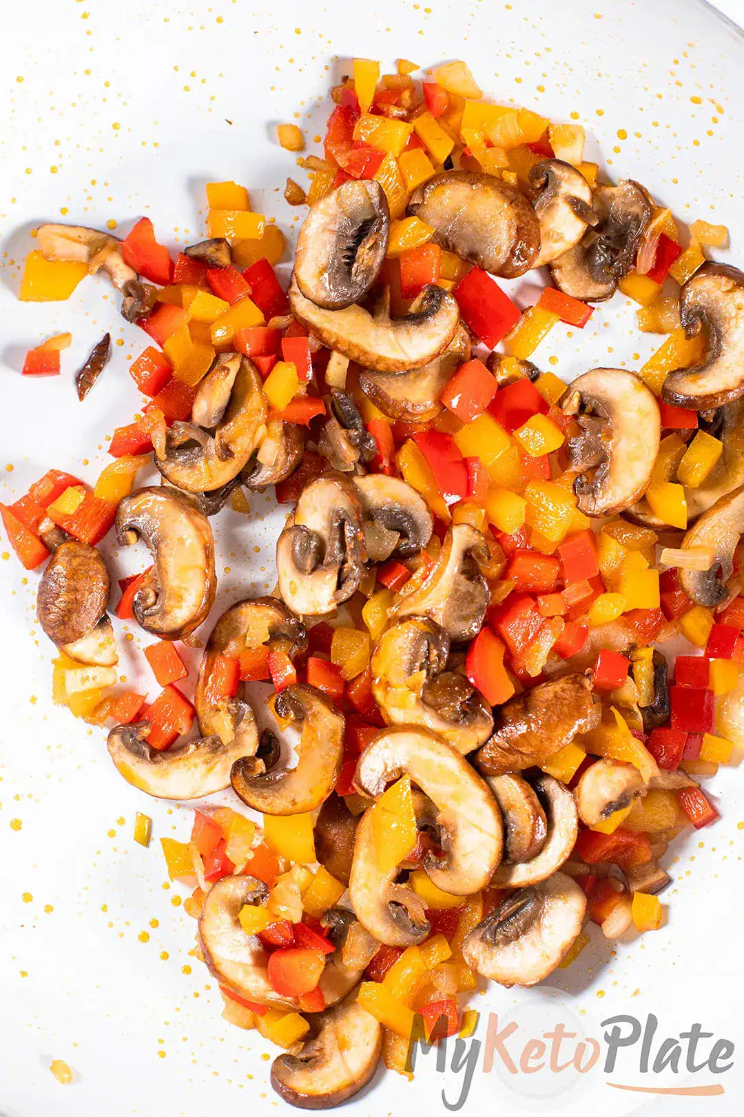 Sautéed mushrooms and diced red and yellow bell peppers cooking together, ready to stuff into chicken breasts.
