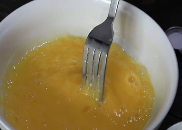 Mixing eggs in a bowl with a fork, preparing batter for 90-second keto bread.