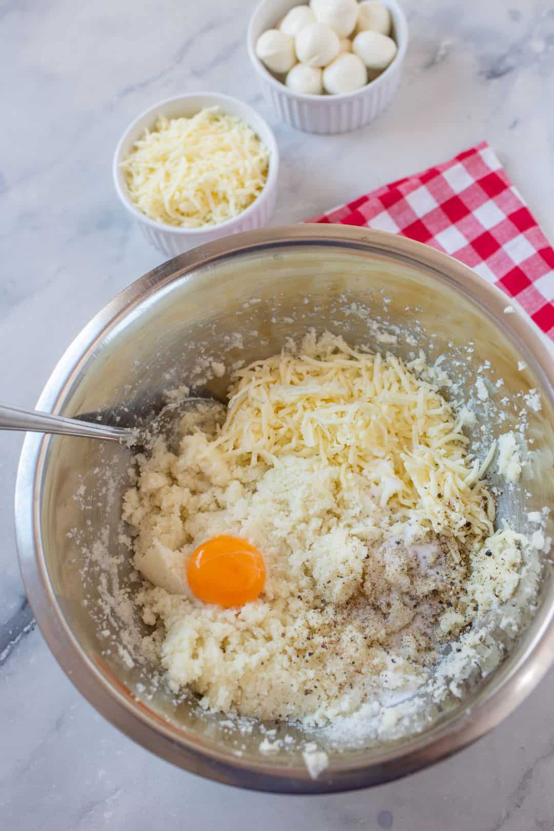 A detailed shot of a keto pizza crust mixture in progress, highlighting fresh ingredients like cheese and cauliflower.
