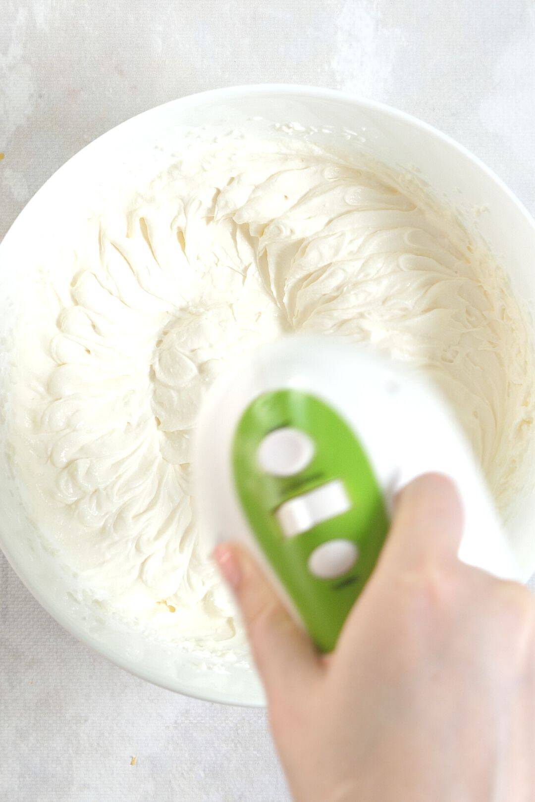 Blending a bowl of homemade keto whipped cream with an electric mixer, creating a smooth and airy texture.