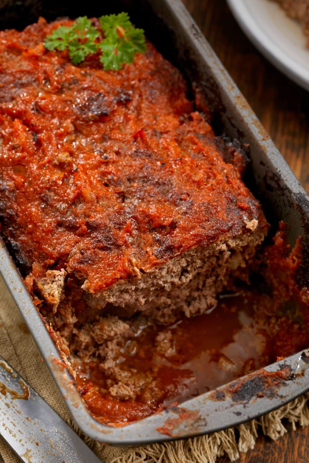 juicy meatloaf recipe in a baking pan with parsley on top