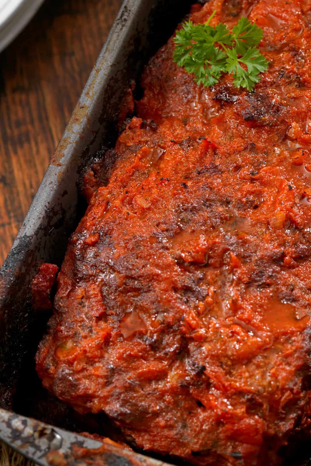 A freshly baked keto meatloaf with a golden-brown crust, topped with a homemade sugar-free sauce.