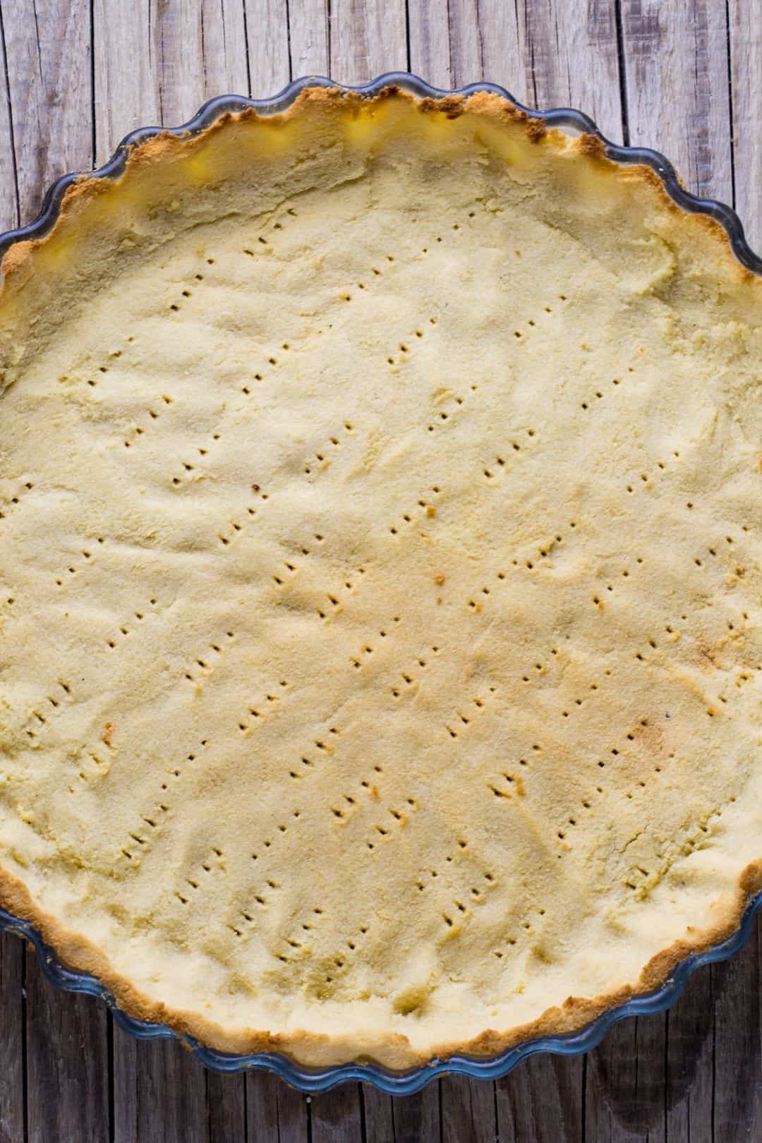 Baked keto pie crust with golden edges in a fluted tart pan.