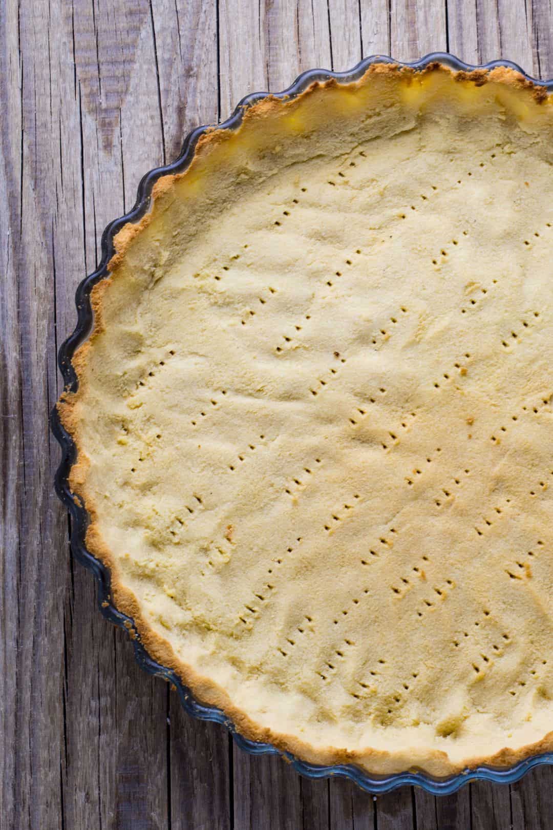 Freshly baked keto crust in a dark non-stick tart dish.
