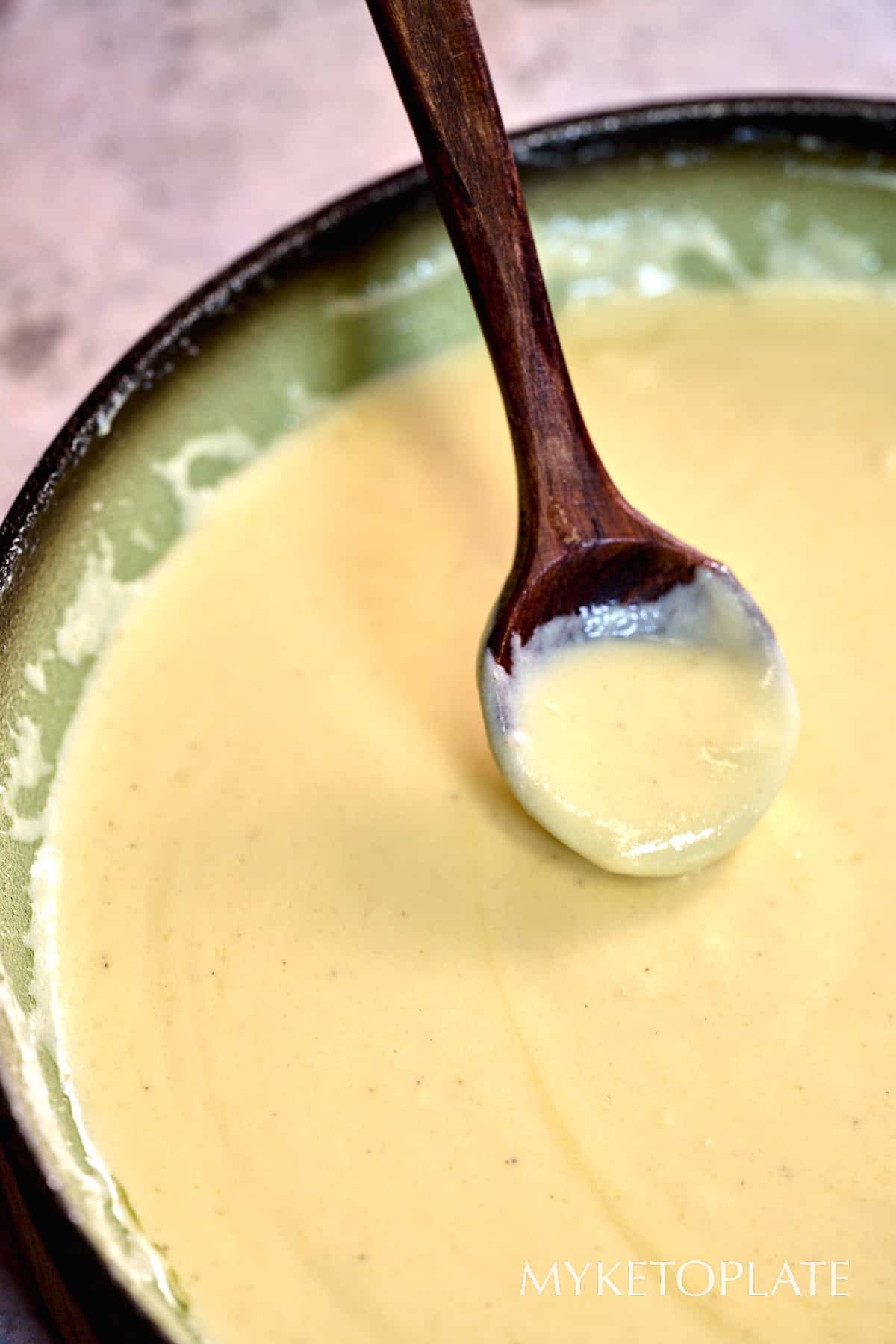 Keto Alfredo Sauce 6 Close-up of smooth keto Alfredo sauce in a pan with a spoon resting in the creamy sauce.