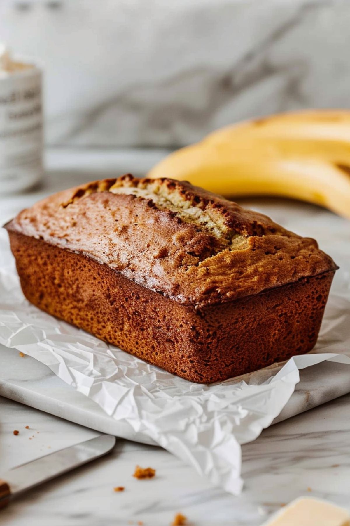Homemade cottage cheese banana bread loaf highlighted against blurred countertop scene.
