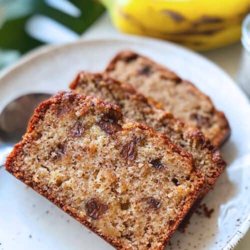Thick slices of cottage-cheese banana bread studded with chocolate chips on a speckled plate.