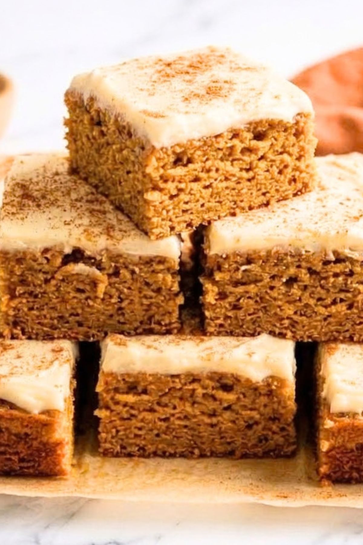 High-Protein Cottage Cheese Pumpkin Bars 5 Stack of High-Protein Cottage Cheese Pumpkin Bars topped with creamy frosting and a sprinkle of cinnamon.