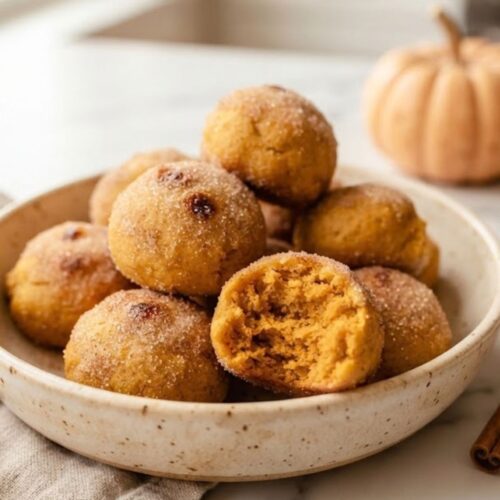 Almond Flour Pumpkin Donut Holes 5 Easy Baked Pumpkin Donut Holes piled in a bowl with a soft, tender center and cinnamon sugar coating.